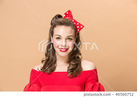 Beautiful young woman with pinup make-up and hairstyle. Studio shot on pastel background Beautiful young woman with pinup make-up and hairstyle. Studio shot on pastel background 40560752