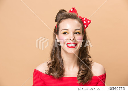 Beautiful young woman with pinup make-up and hairstyle. Studio shot on pastel background Beautiful young woman with pinup make-up and hairstyle. Studio shot on pastel background 40560753