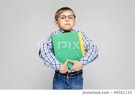 A charming boy with a vkletchatoy shirt and light jeans stands on a gray background. The boy holds 40561119
