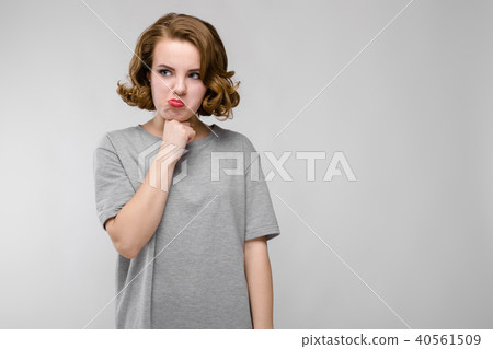 Charming young girl in a gray T-shirt on a gray background. The girl pinned her chin 40561509