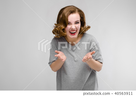 Charming young girl in a gray T-shirt on a gray background. The girl leads a dialogue Charming young girl in a gray T-shirt on a gray background. The girl leads a dialogue 40563911