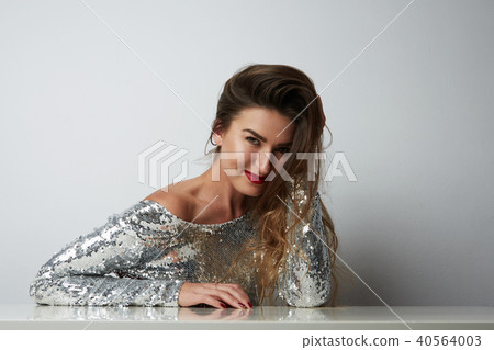 Fashion portrait of a beautiful smiling woman with long hair in a pretty silver dress with tinsel Fashion portrait of a beautiful smiling woman with long hair in a pretty silver dress with tinsel 40564003