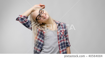 Beautiful teen girl with long hair and wearing glasses. A teenage girl in a plaid shirt and a gray T Beautiful teen girl with long hair and wearing glasses. A teenage girl in a plaid shirt and a gray T 40564084