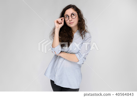 Portrait of a young girl in glasses. Beautiful young girl on a gray background. A young girl in a 40564843