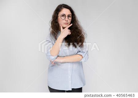 Portrait of a young girl in glasses. Beautiful young girl on a gray background. A young girl in a 40565463