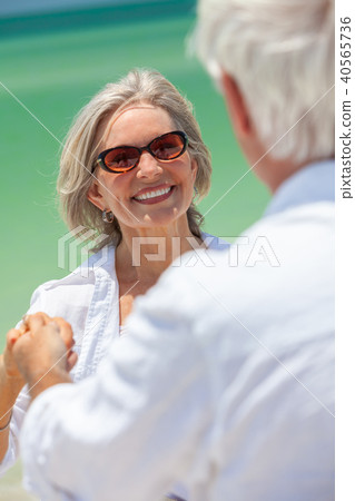 Happy Senior Couple Holding Hands on a Beach 40565736