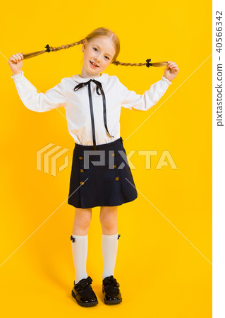 Girl with red pigtails on a yellow background. A beautiful girl is holding her pigtails 40566342