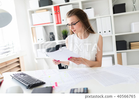A young girl in the office is holding a sheet. 40566765