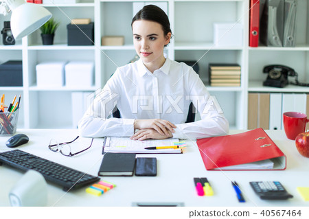 A young girl is sitting at the computer desk in the office. 40567464