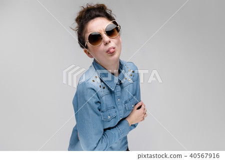Young brunette girl in black glasses. Cat glasses. The hair is gathered in a bun. The girl shows her Young brunette girl in black glasses. Cat glasses. The hair is gathered in a bun. The girl shows her 40567916