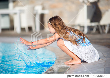 Little girl having fun with a splash near swimming pool 40568668