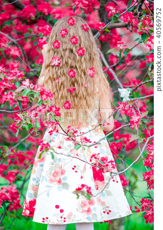 Adorable little girl in blooming apple tree garden on spring day Adorable little girl in blooming apple tree garden on spring day 40569752