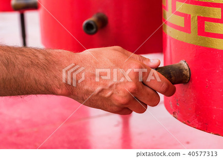 Hand touches red buddhist prayer wheel close Hand touches red buddhist prayer wheel close 40577313