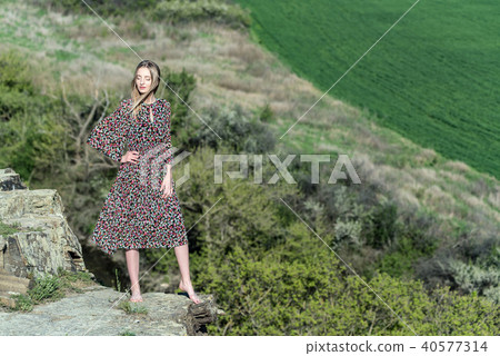 Beautiful girl in dress poses on rock in nature Beautiful girl in dress poses on rock in nature 40577314
