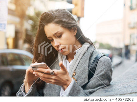Woman using her mobile phone in the street. 40578208