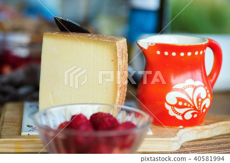 Gruyere cheese, red pitcher and raspberry. 40581994