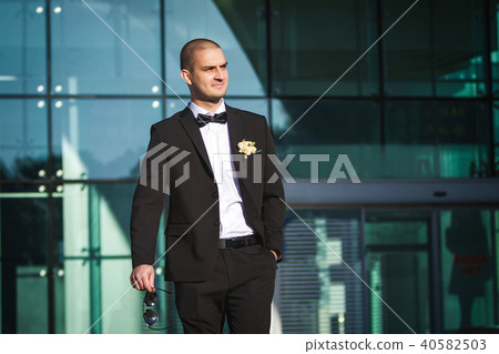 handsome smiling groom holding sunglasses 40582503