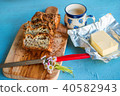 Gluten-free seed bread, butter and cup of drink. 40582943
