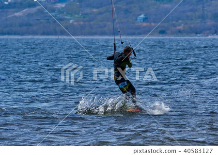 male kiteboarder rides on a board on a large river male kiteboarder rides on a board on a large river 40583127