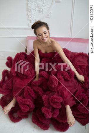 Cheerful young woman in a burgundy ball gown. 40585572