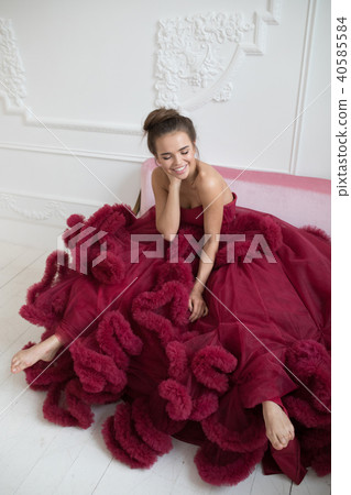 Cheerful young woman in a burgundy ball gown. 40585584