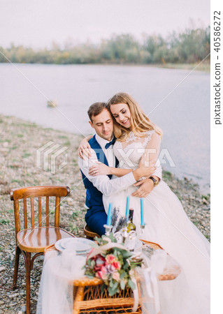 Sensitive outdoor portrait of the bride sitting on the groom on the coast. Sensitive outdoor portrait of the bride sitting on the groom on the coast. 40586272