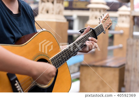 Man playing acoustic guitar with a capo clip 40592369