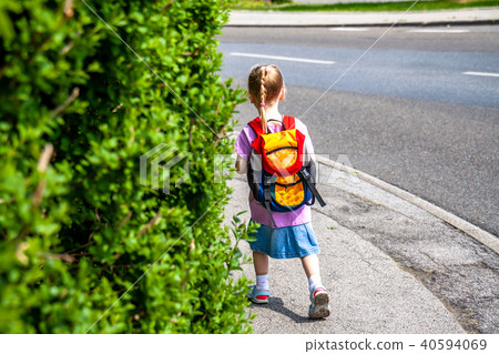 Little girls walking away with her filled backpack Little girls walking away with her filled backpack 40594069