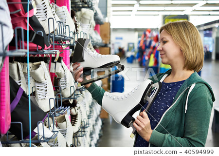 Woman chooses figure skates in sports shop Woman chooses figure skates in sports shop 40594999