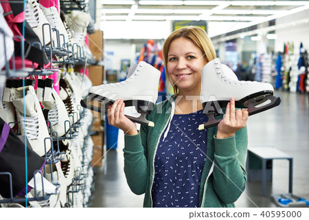 Happy woman with figure skates in the sports shop Happy woman with figure skates in the sports shop 40595000