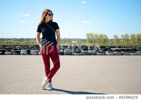 Stylishly dressed young woman in glasses stands in the middle of a stone square against the Stylishly dressed young woman in glasses stands in the middle of a stone square against the 40596029
