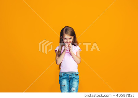 The happy teen girl standing and smiling against orange background. The happy teen girl standing and smiling against orange background. 40597855
