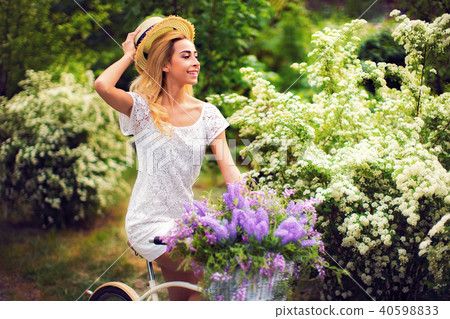 beautiful young girl with vintage bicycle and flowers on city background in the sunlight outdoor. beautiful young girl with vintage bicycle and flowers on city background in the sunlight outdoor. 40598833