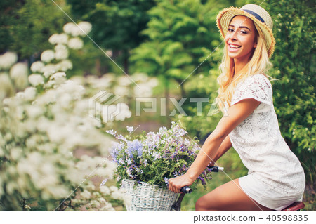beautiful young girl with vintage bicycle and flowers on city background in the sunlight outdoor. beautiful young girl with vintage bicycle and flowers on city background in the sunlight outdoor. 40598835