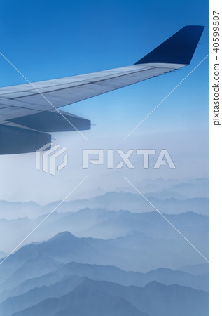 Airplane wing above mountains in a fog Airplane wing above mountains in a fog 40599807