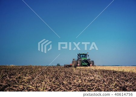 Tractor plowing farm field in preparation for spring planting. 40614756