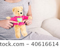 Pregnant woman hand holding teddy bear doll. 40616614