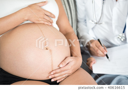 Pregnant woman holding hand on belly with doctor. 40616615