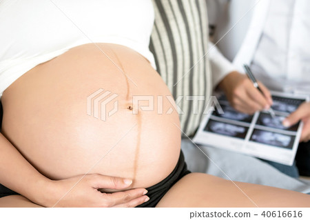 Pregnant woman holding hand on belly and doctor. 40616616