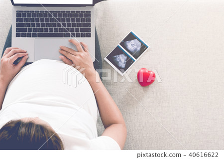 Pregnant woman is shopping online with laptop. 40616622