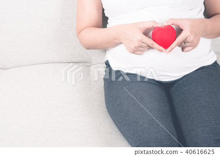 Happy pregnant woman holding love red heart shape. 40616625