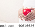 Happy pregnant woman holding love red heart shape. 40616626