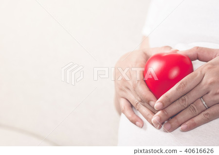 Happy pregnant woman holding love red heart shape. 40616626