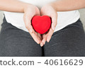 Happy pregnant woman holding love red heart shape. 40616629