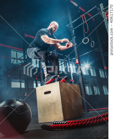 Man jumping during exercises in the fitness gym. CrossFit. Man jumping during exercises in the fitness gym. CrossFit. 40617170