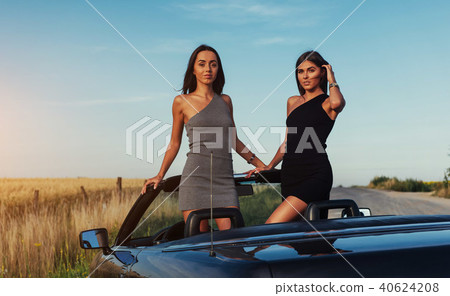 Beautiful two women sitting in a convertible Beautiful two women sitting in a convertible 40624208