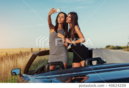 Two sexy brunette woman standing near cabriolet Two sexy brunette woman standing near cabriolet 40624209