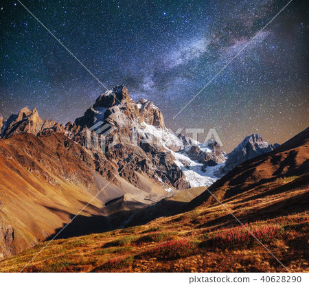 Fantastic starry sky. Autumn landscape and snow-capped peaks. Ma 40628290