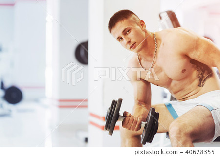 Beautiful athletic bodybuilder guy, carries out exercises with d Beautiful athletic bodybuilder guy, carries out exercises with d 40628355