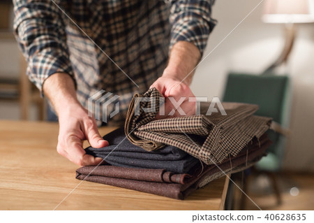 Selects wool from the stack. Young man working as a tailor and using a sewing machine in workshop. 40628635